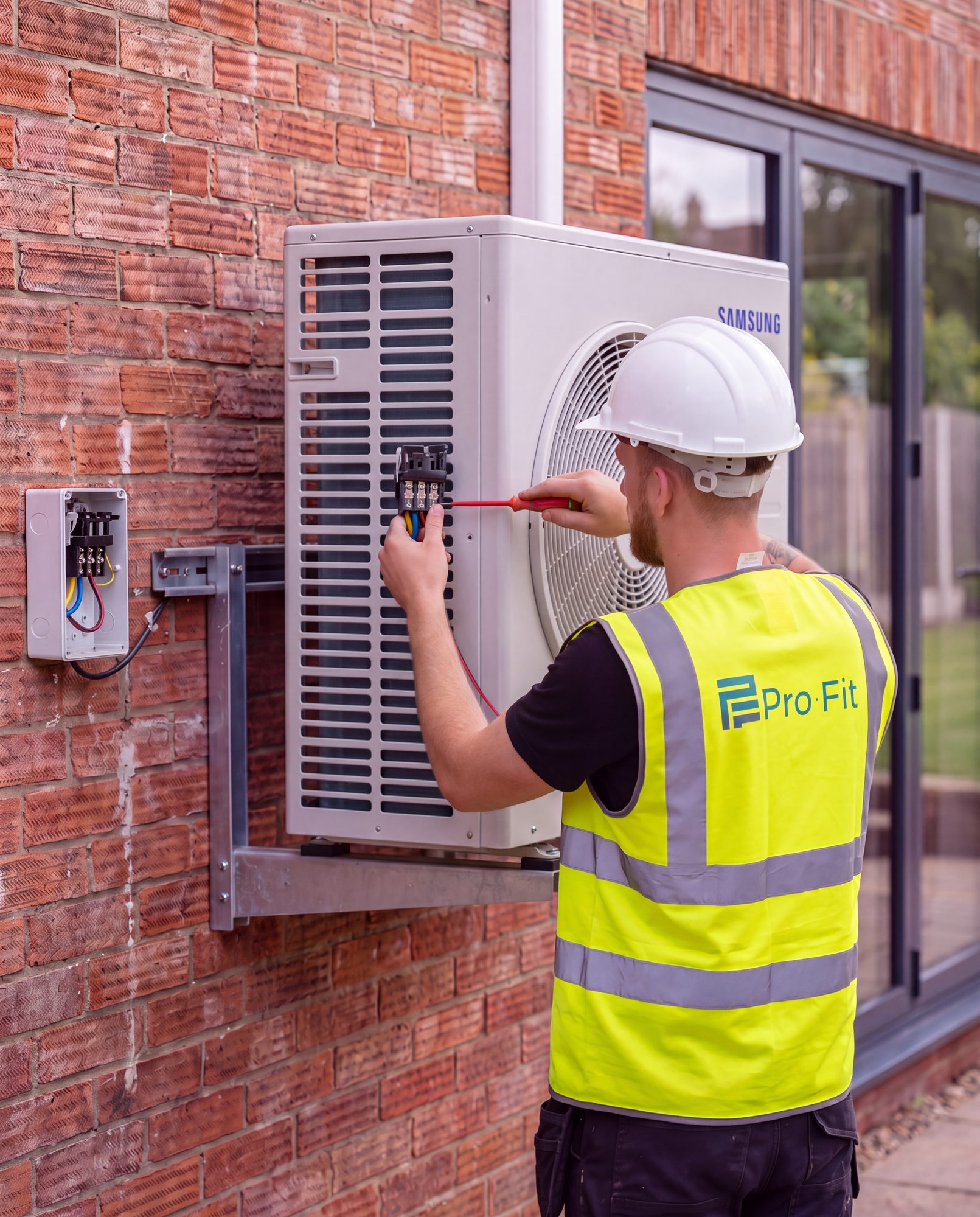 A Pro-Fit engineer wiring the isolator beside a Samsung outdoor air conditioning unit