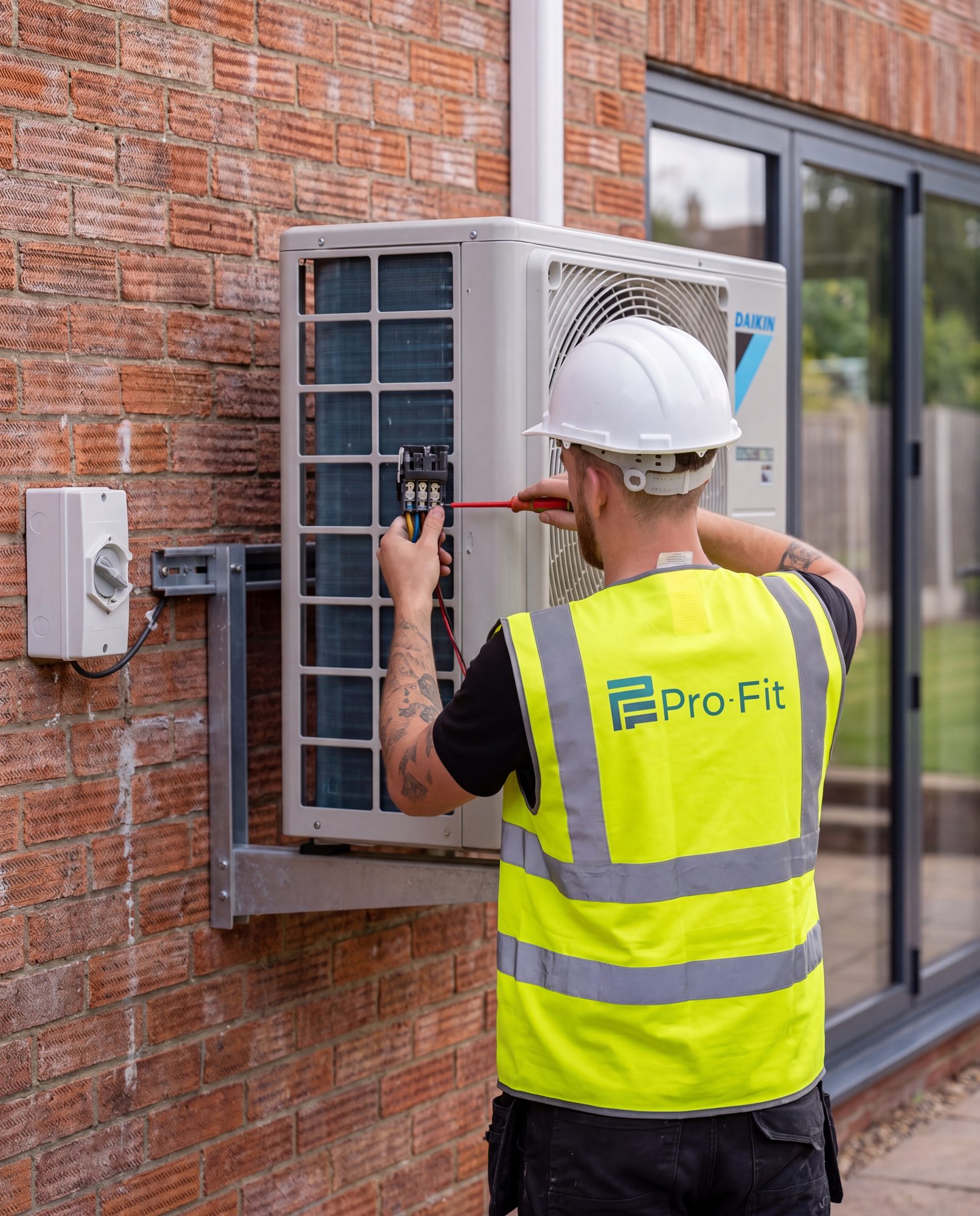 A Pro-Fit engineer wiring a Daikin outdoor unit at a customer's home